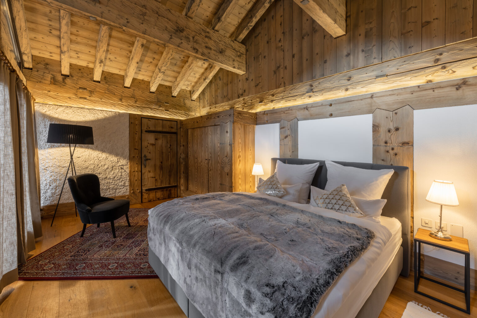 Schlafzimmer mit Holzdecke in einer Ferienwohnung von Saas Holidays im Saastal